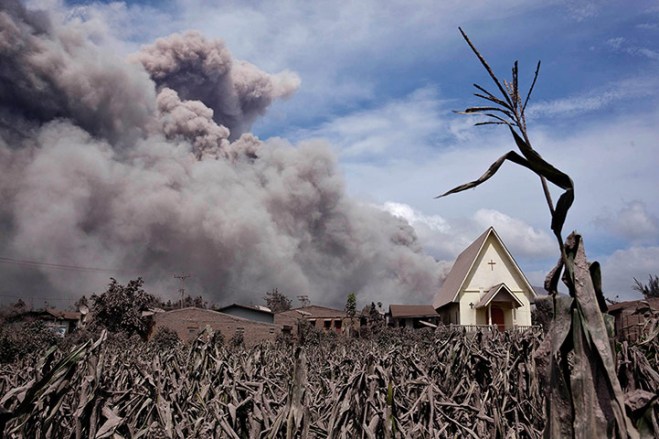 De aswolken van de Sinabung-vulkaan, met op de voorgrond de kerk van het dorpje Sibintun.