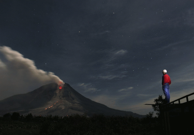 Een man kijkt uit op de Sinabung-vulkaan.