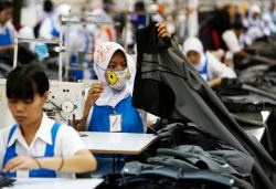 Worker holds part of a pair of trousers at PT Trisula Garmindo Manufacturing in Bandung